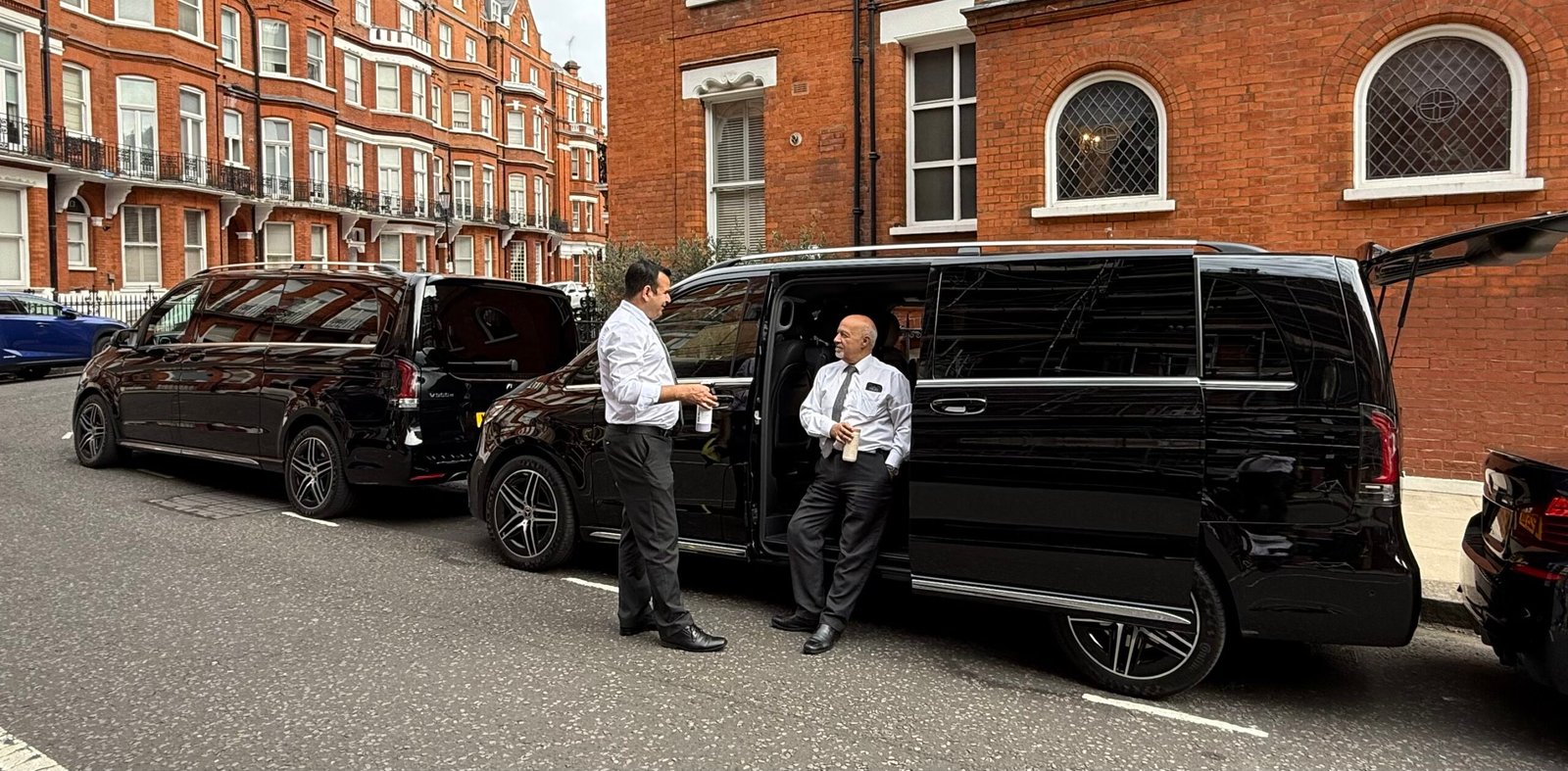 Black Royale chauffeur greeting a client beside a black Mercedes V-Class in London