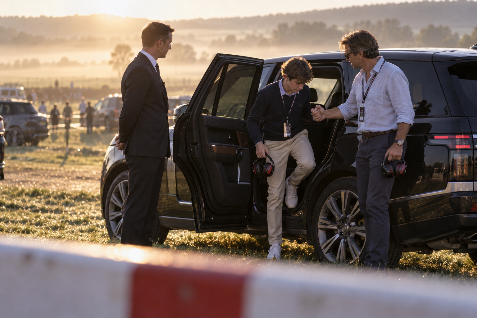 Chauffeur meeting race-day guests beside a black Range Rover at a motorsport circuit